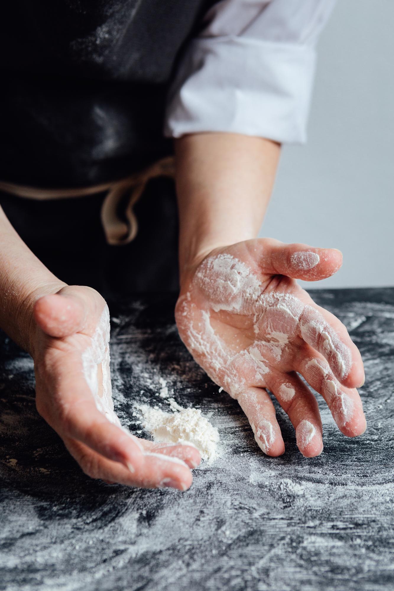Close-up of hands kneading dough on a floured board