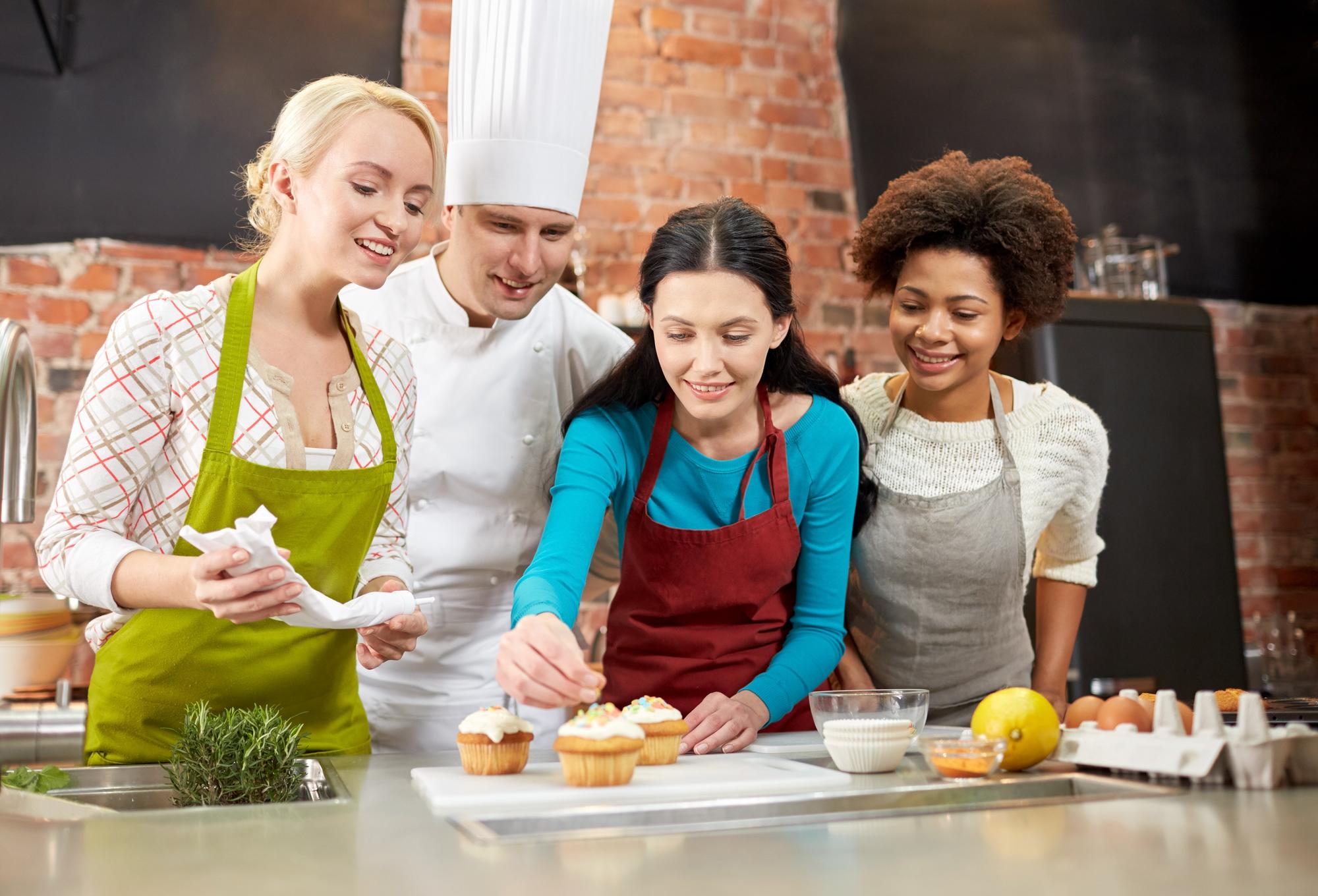 Instructor smiling while teaching a small group in a bright kitchen